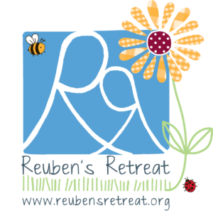 Logo of Reuben's Retreat featuring stylized white 'RR' initials on a sky-blue background with a bee on the top left and a cheerful daisy on the right. Below, the text reads 'Reuben's Retreat' above a field of green grass with a ladybug, and the website 'www.reubensretreat.org' is at the bottom. The color scheme is playful with a black border framing the design.